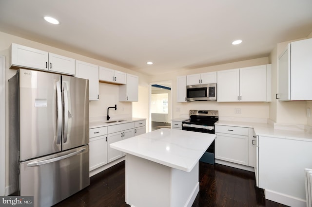 kitchen featuring a kitchen island, dark hardwood / wood-style flooring, white cabinetry, and appliances with stainless steel finishes