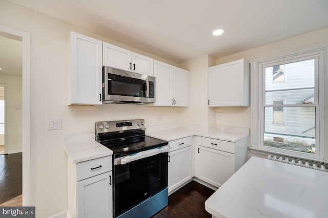 kitchen with white cabinets, light stone countertops, stainless steel appliances, and dark wood-type flooring