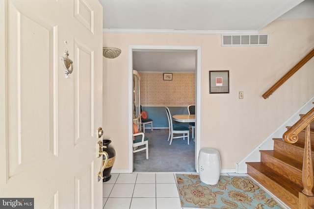 foyer entrance with light tile patterned floors and ornamental molding