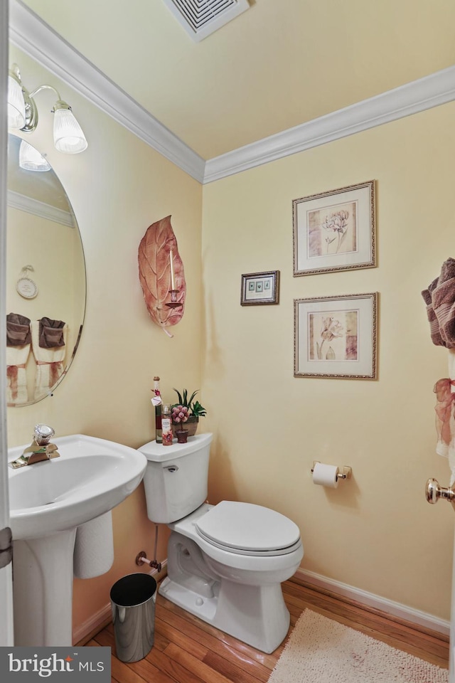 bathroom featuring crown molding, hardwood / wood-style floors, and toilet