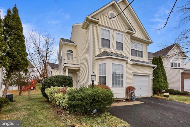 view of front facade with a front lawn, a balcony, cooling unit, and a garage