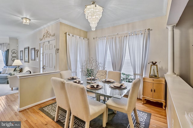 dining area with ornate columns, crown molding, and light hardwood / wood-style flooring