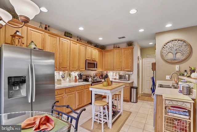 kitchen with sink, light tile patterned floors, stainless steel appliances, and light brown cabinetry