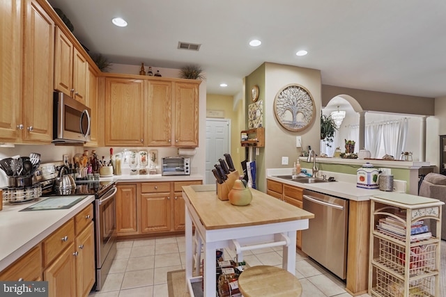 kitchen with sink, light tile patterned flooring, stainless steel appliances, and a kitchen island