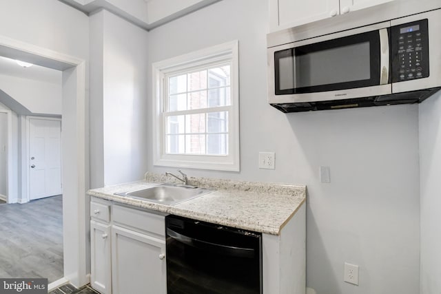 kitchen featuring sink, dishwasher, light hardwood / wood-style floors, light stone countertops, and white cabinets