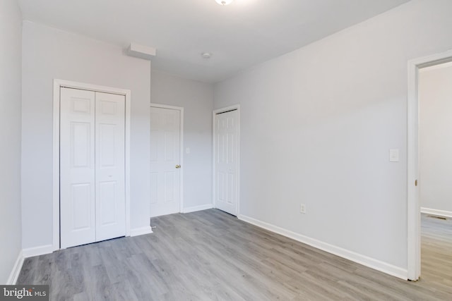 unfurnished bedroom with light hardwood / wood-style floors and two closets