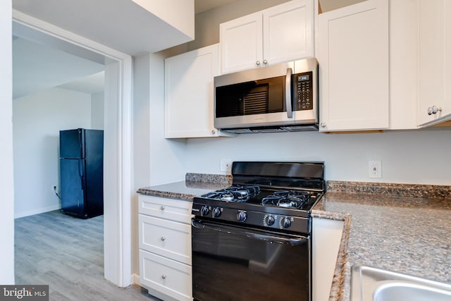 kitchen with white cabinets, light hardwood / wood-style floors, and black appliances