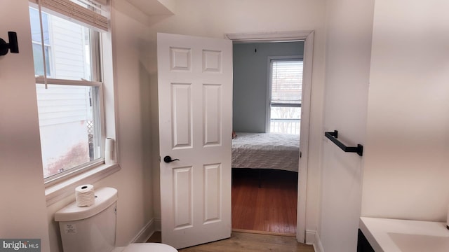 bathroom with wood finished floors, toilet, and baseboards