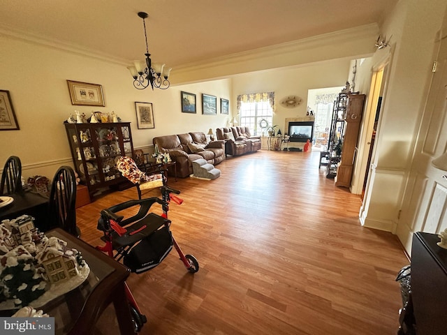 living room featuring light hardwood / wood-style flooring, an inviting chandelier, and ornamental molding