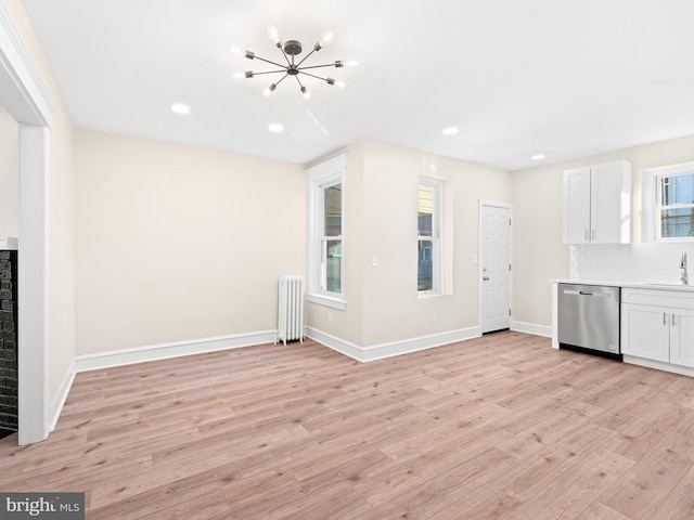 interior space featuring radiator heating unit, white cabinetry, stainless steel dishwasher, and light hardwood / wood-style flooring