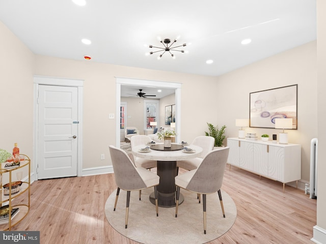 dining area with ceiling fan with notable chandelier, light hardwood / wood-style floors, and radiator