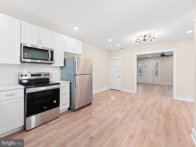 kitchen featuring appliances with stainless steel finishes, light hardwood / wood-style floors, white cabinetry, and tasteful backsplash