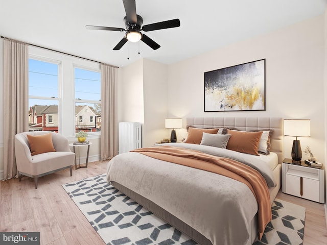 bedroom featuring ceiling fan, light wood-type flooring, and radiator