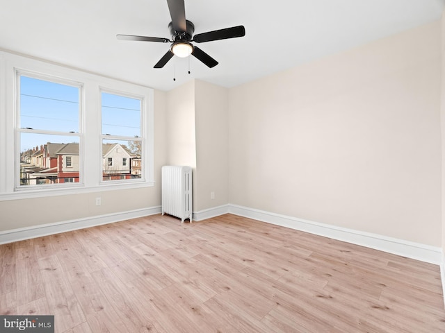 unfurnished room with light wood-type flooring, radiator, and ceiling fan