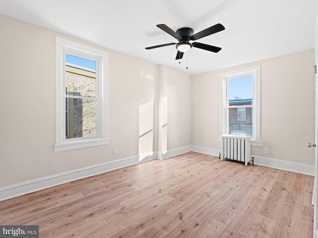 spare room with ceiling fan, light hardwood / wood-style floors, and radiator heating unit