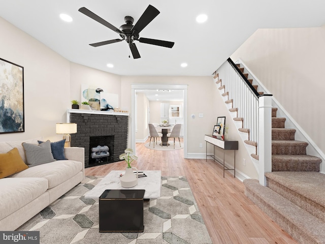 living room featuring a fireplace, hardwood / wood-style floors, and ceiling fan