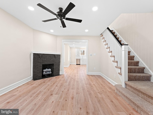 unfurnished living room featuring ceiling fan, light wood-type flooring, and a fireplace