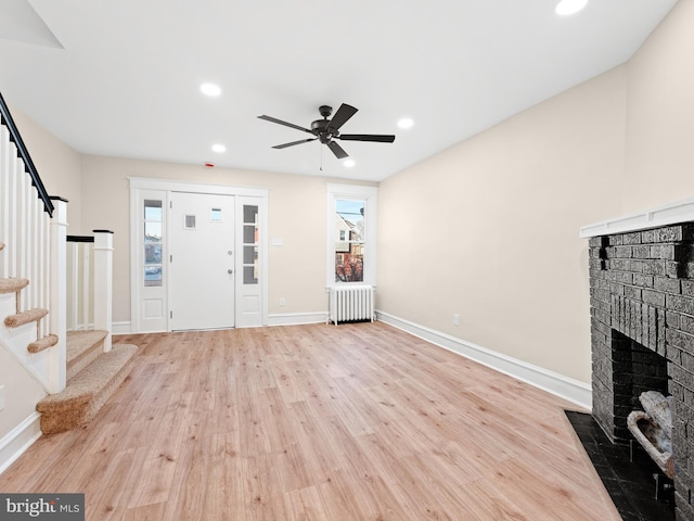 entrance foyer with radiator, ceiling fan, a healthy amount of sunlight, and light wood-type flooring