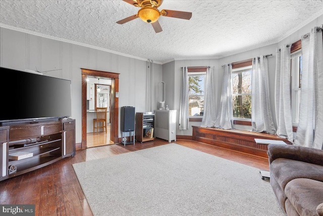 living room featuring a textured ceiling, ceiling fan, dark hardwood / wood-style floors, and ornamental molding