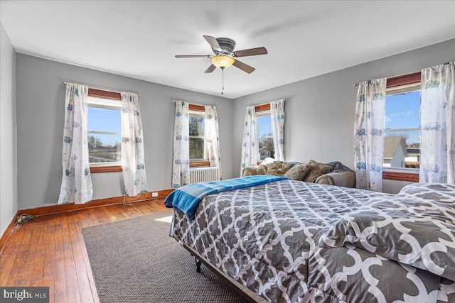 bedroom with multiple windows, ceiling fan, and hardwood / wood-style floors