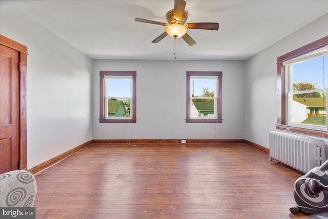 empty room with radiator heating unit, a healthy amount of sunlight, and light hardwood / wood-style floors