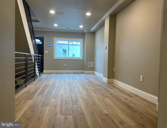 unfurnished living room with light wood-type flooring and crown molding