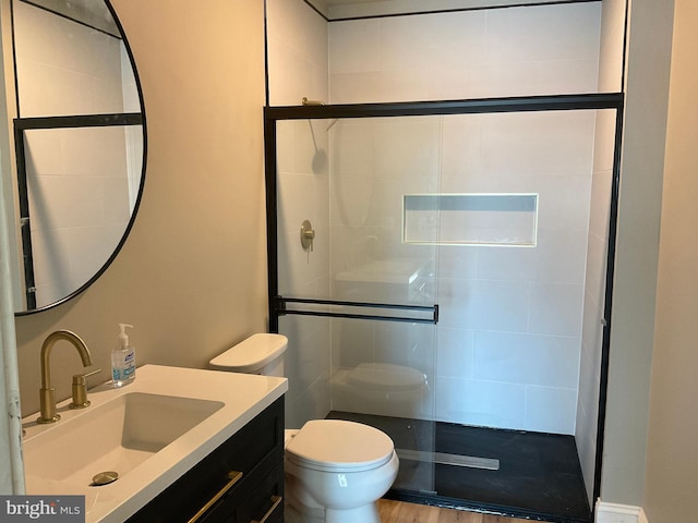 bathroom with hardwood / wood-style floors, vanity, toilet, and a shower with door