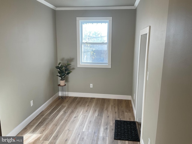 empty room with crown molding and light hardwood / wood-style floors