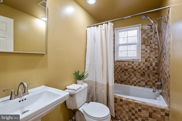 full bathroom featuring shower / bath combination with curtain, toilet, and sink