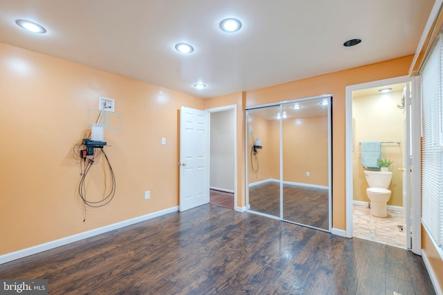 unfurnished bedroom featuring dark hardwood / wood-style flooring, connected bathroom, and a closet