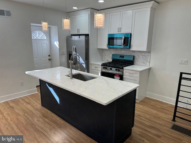 kitchen featuring a center island with sink, decorative light fixtures, sink, and stainless steel appliances