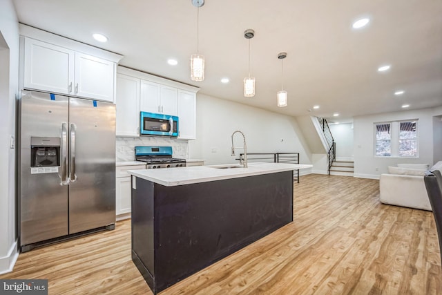 kitchen with white cabinetry, hanging light fixtures, stainless steel appliances, and light hardwood / wood-style floors