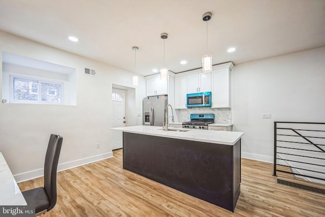 kitchen featuring sink, hanging light fixtures, light hardwood / wood-style flooring, white cabinetry, and stainless steel appliances