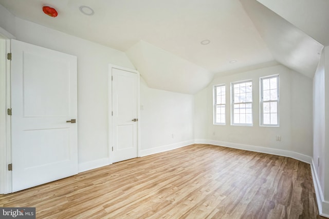 additional living space with light wood-type flooring and lofted ceiling