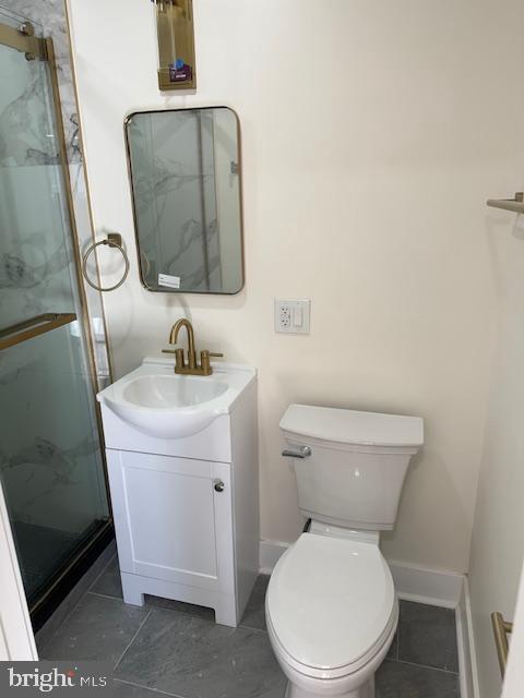 bathroom featuring tile patterned flooring, vanity, toilet, and a shower with door