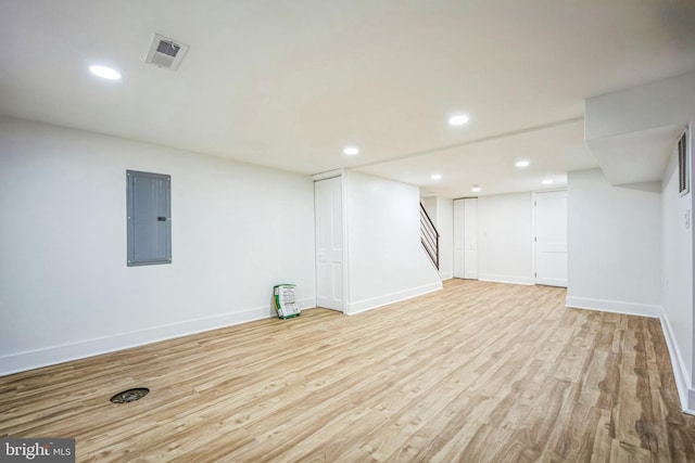 basement with light wood-type flooring and electric panel