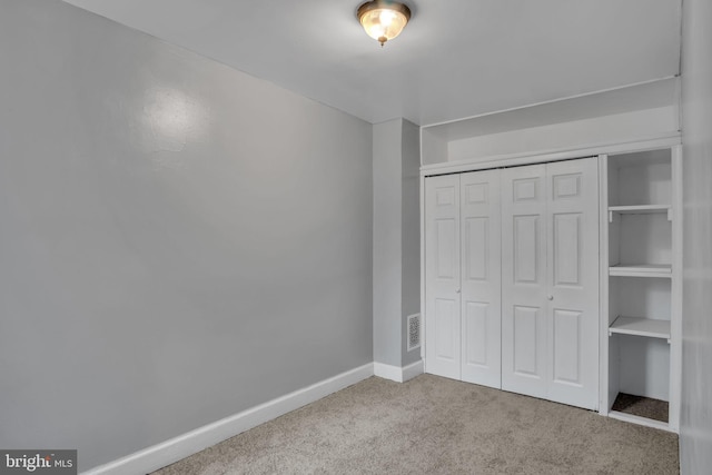 unfurnished bedroom with light carpet and a closet