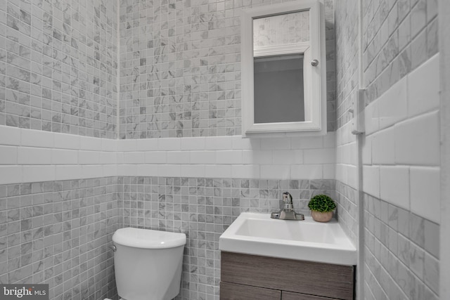 bathroom with vanity, toilet, and tile walls