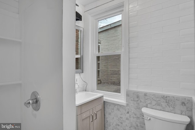 bathroom featuring vanity, tile walls, and toilet