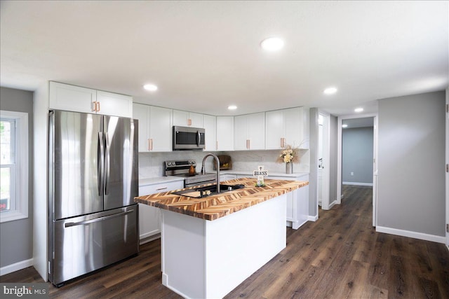 kitchen featuring stainless steel appliances, white cabinetry, and a center island with sink