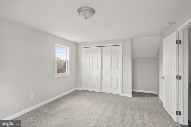 unfurnished bedroom featuring a closet, carpet, and vaulted ceiling