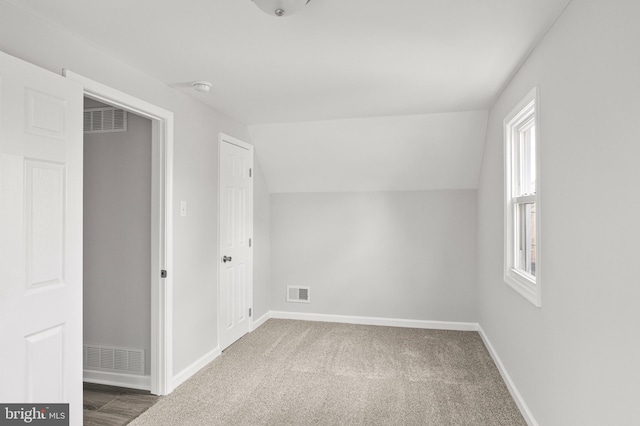 bonus room with dark carpet, vaulted ceiling, and a healthy amount of sunlight