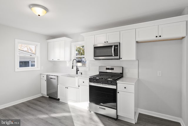 kitchen with sink, white cabinetry, stainless steel appliances, and a wealth of natural light