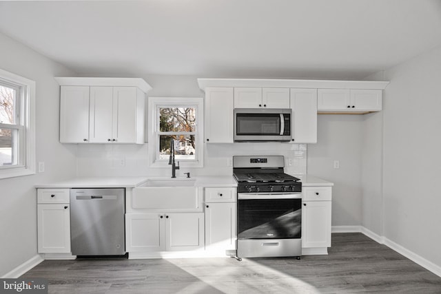 kitchen featuring appliances with stainless steel finishes, white cabinetry, a healthy amount of sunlight, and hardwood / wood-style floors