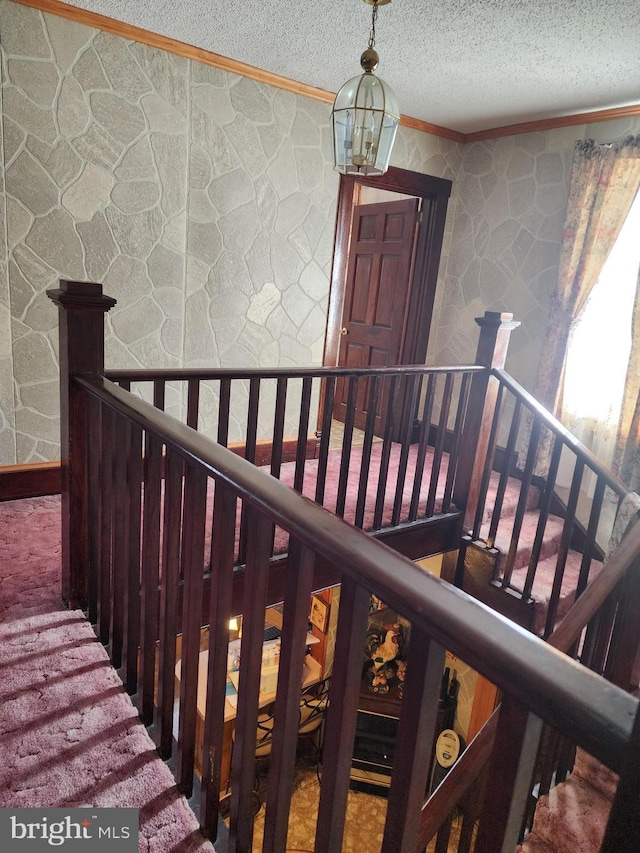 interior space featuring an inviting chandelier, carpet, a textured ceiling, and ornamental molding