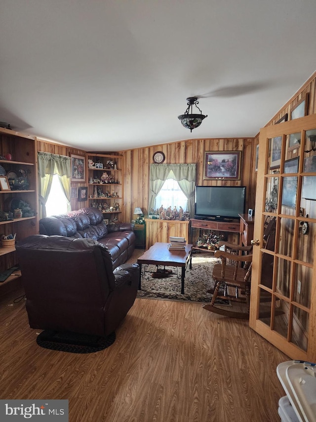 living room featuring lofted ceiling, a wealth of natural light, and wooden walls