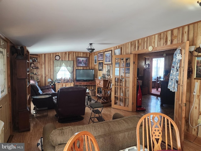 living room featuring dark hardwood / wood-style floors, a healthy amount of sunlight, wooden walls, and french doors