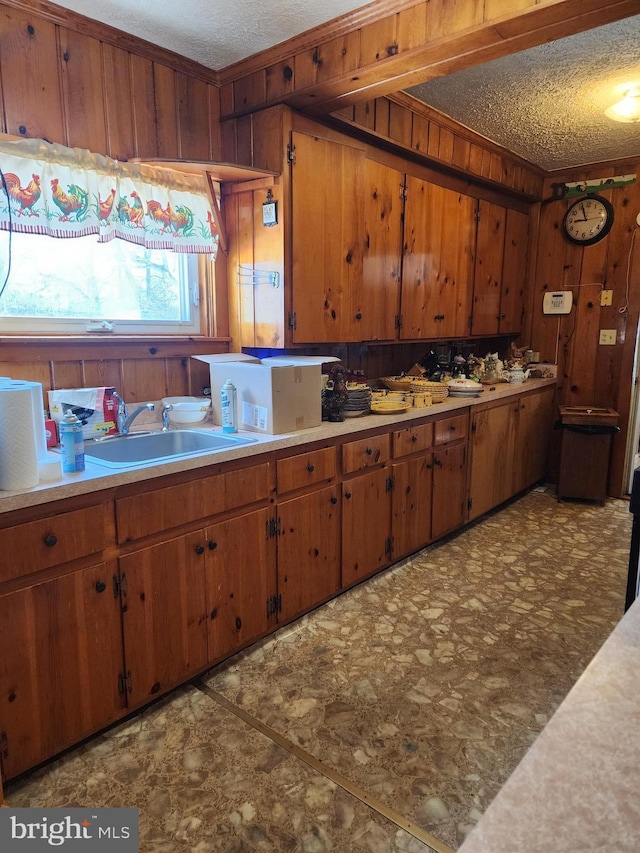 kitchen with a textured ceiling, wood walls, and sink