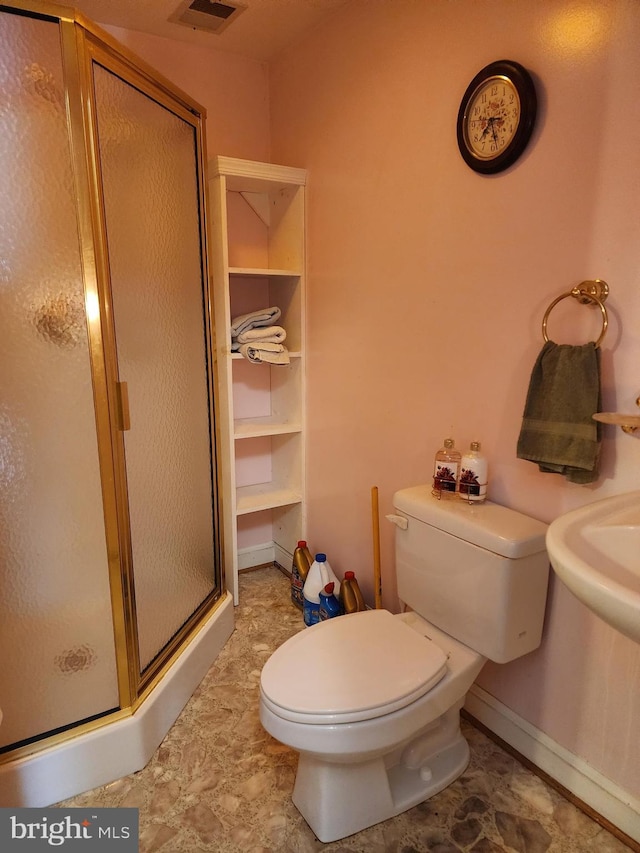 bathroom featuring a shower with shower door and toilet