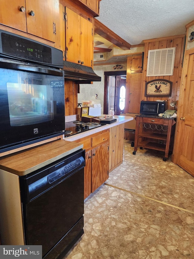 kitchen with beamed ceiling, black appliances, and a textured ceiling